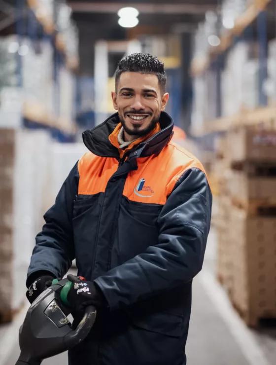 Un homme qui sourit debout dans un entrepôt de logistique