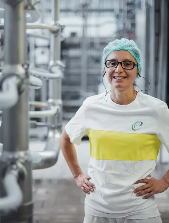 Une femme qui sourit, elle debout dans une usine